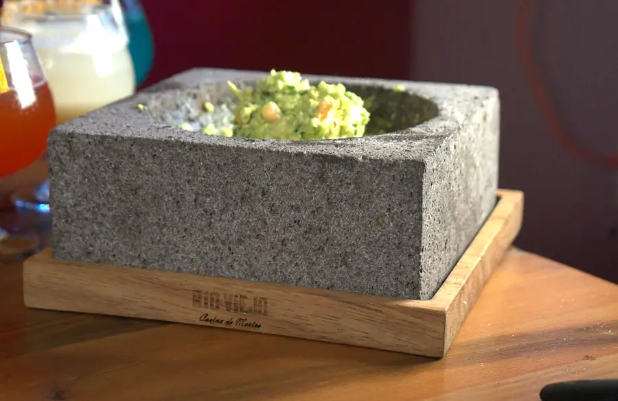 Fresh tableside guacamole served in a Rio Viejo branded molcajete with margaritas